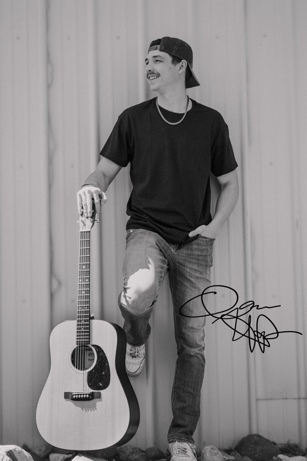 Isaac Harper standing with his acoustic guitar, signed
